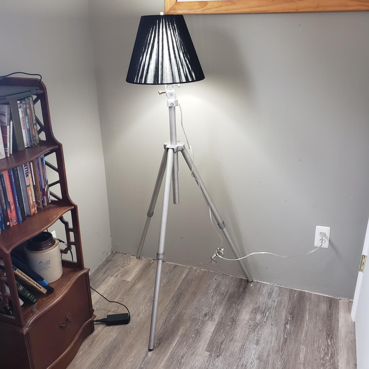 tripod base supporting shaded lamp