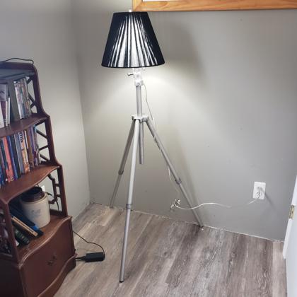 tripod base supporting shaded lamp
